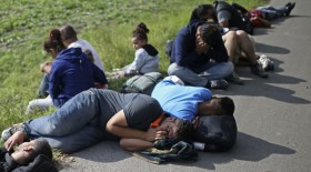 Migrants sit on the ground after being detained by police in Morahalom